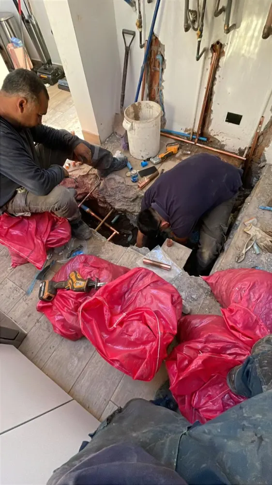 Dos integrantes del equipo SafeRed trabajando en cañerías bajo piso